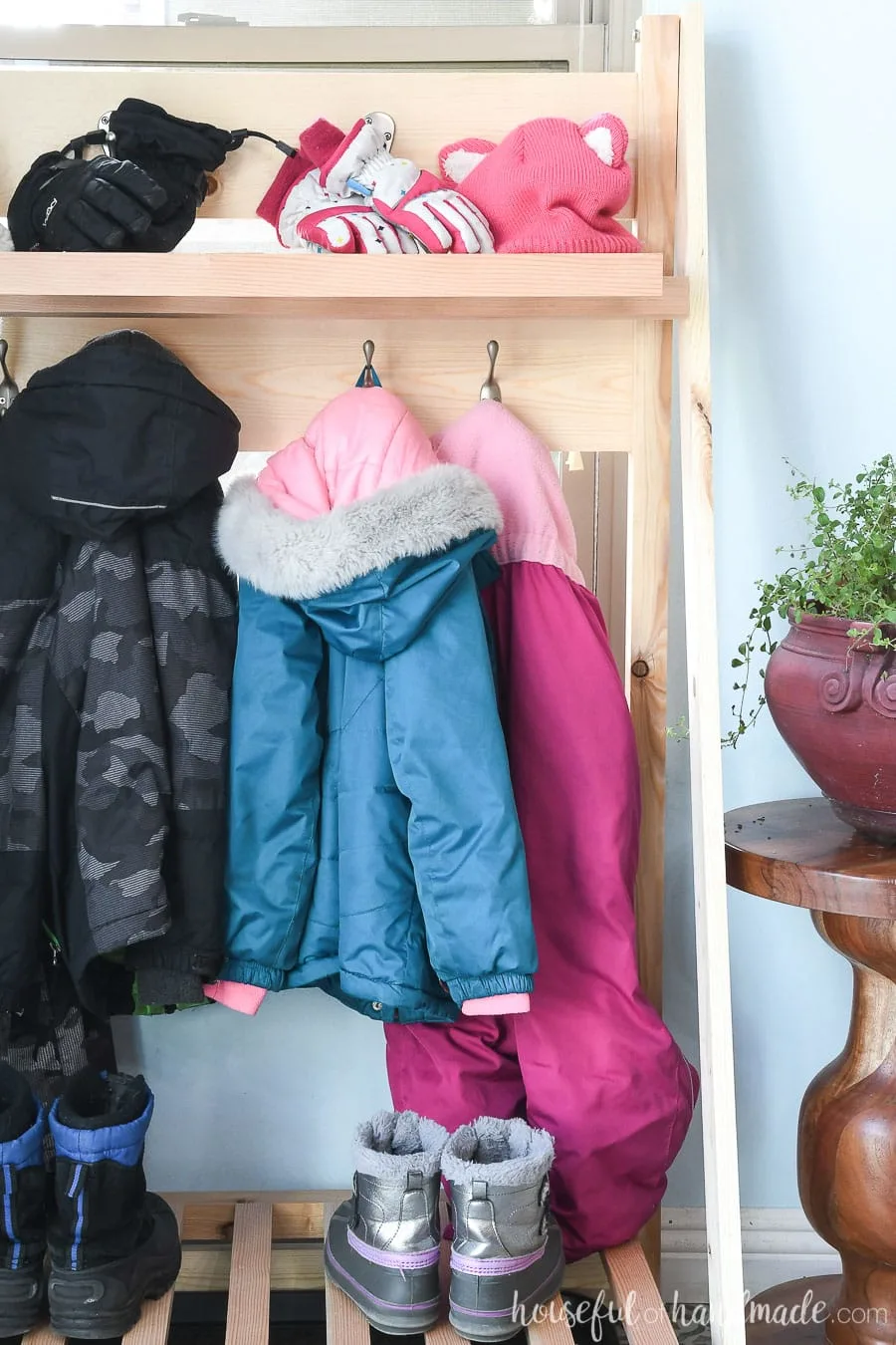 View of the fold-away mudroom shelves with coats and winter gear hanging on it. 