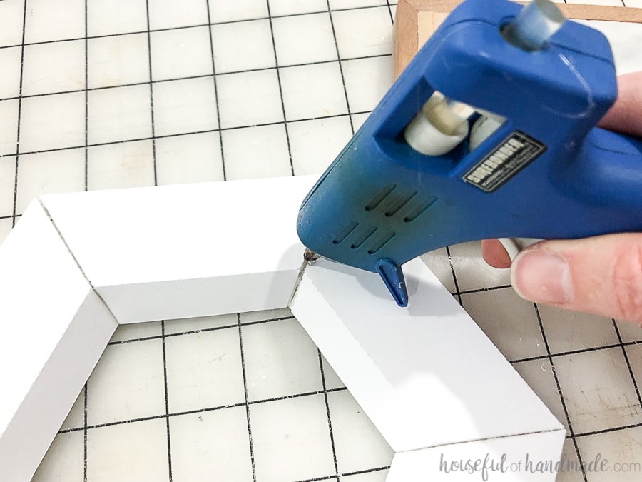 Filling the seams of the hexagon wall mirror with hot glue.