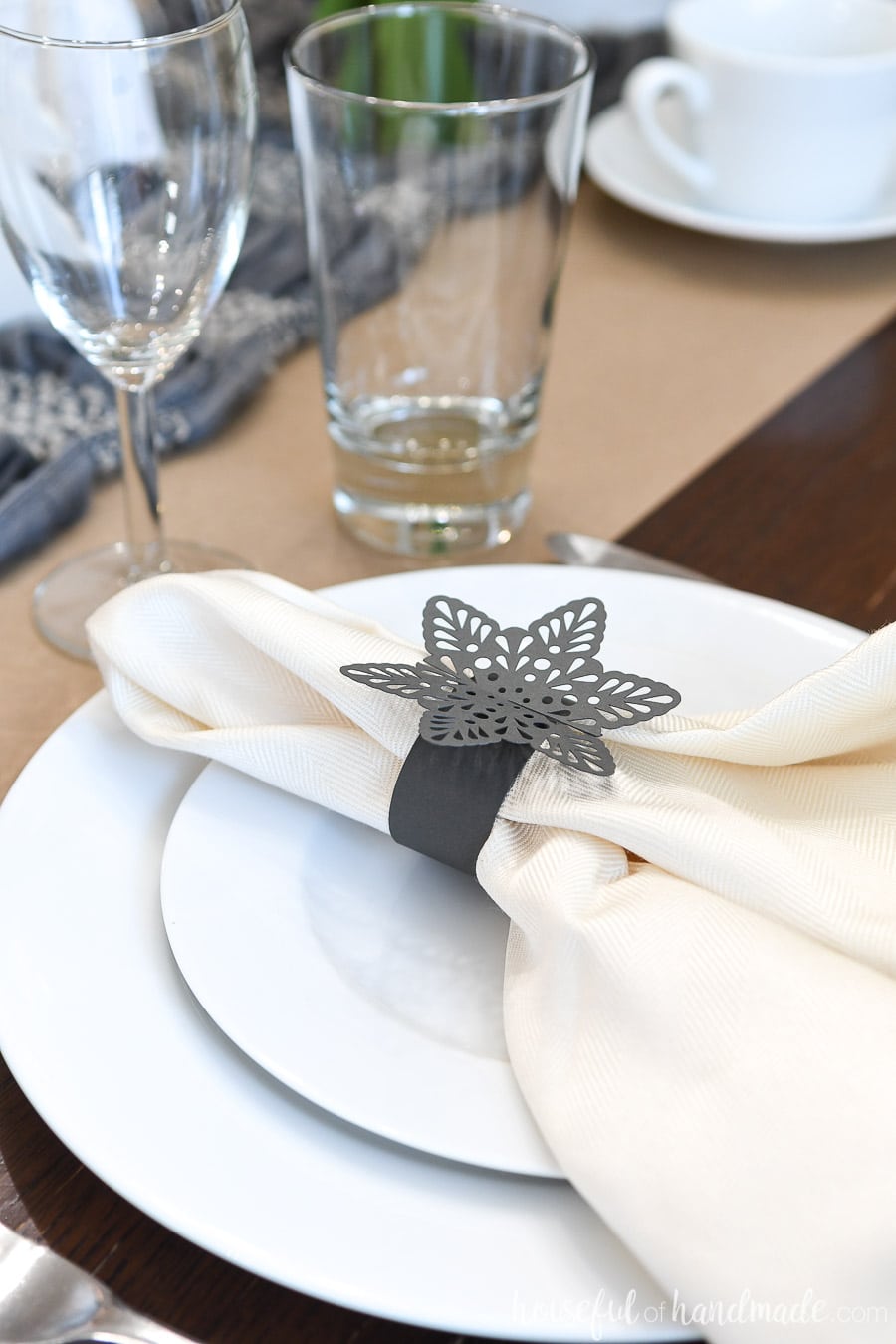 Close-up view of the table setting on the winter tablescape with snowflake paper napkin rings on the plates.