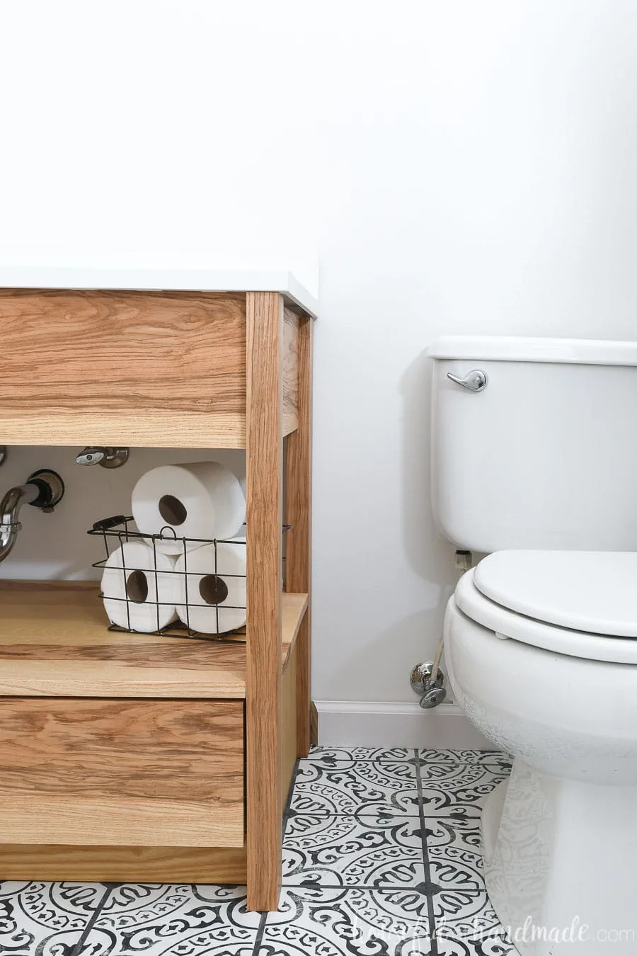 Open shelf modern bathroom vanity with drawers on the bottom in a bathroom with black & white patterned tile floor.