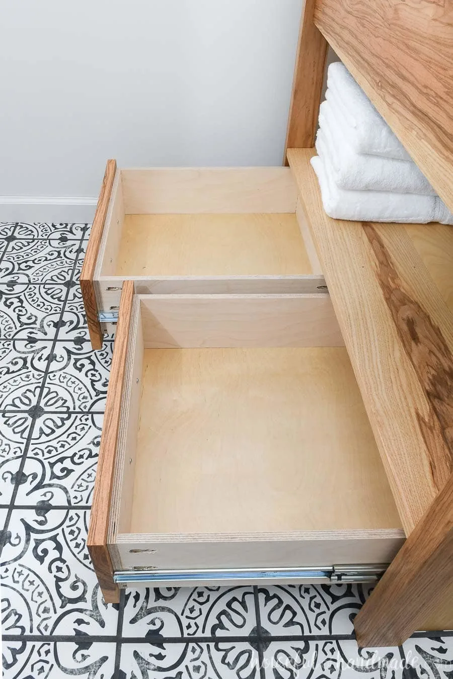 Drawers of the modern bathroom vanity open showing the storage space. 