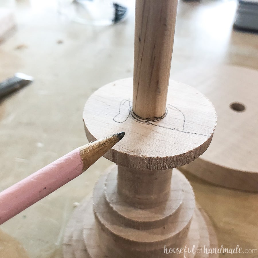 Marking a line on the dowel sticking out of the base of the DIY cake stand. 