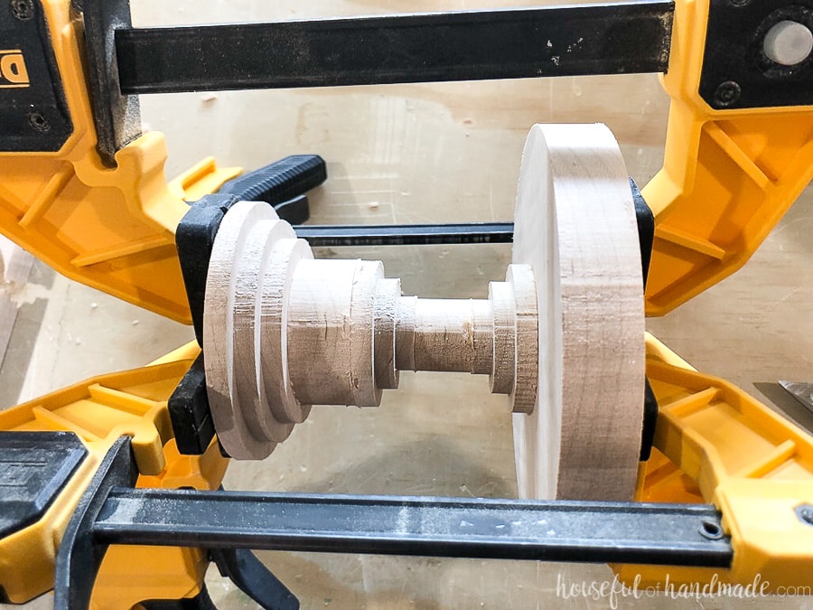 Four Dewalt clamps holding the wooden cake stand together while the glue dries.