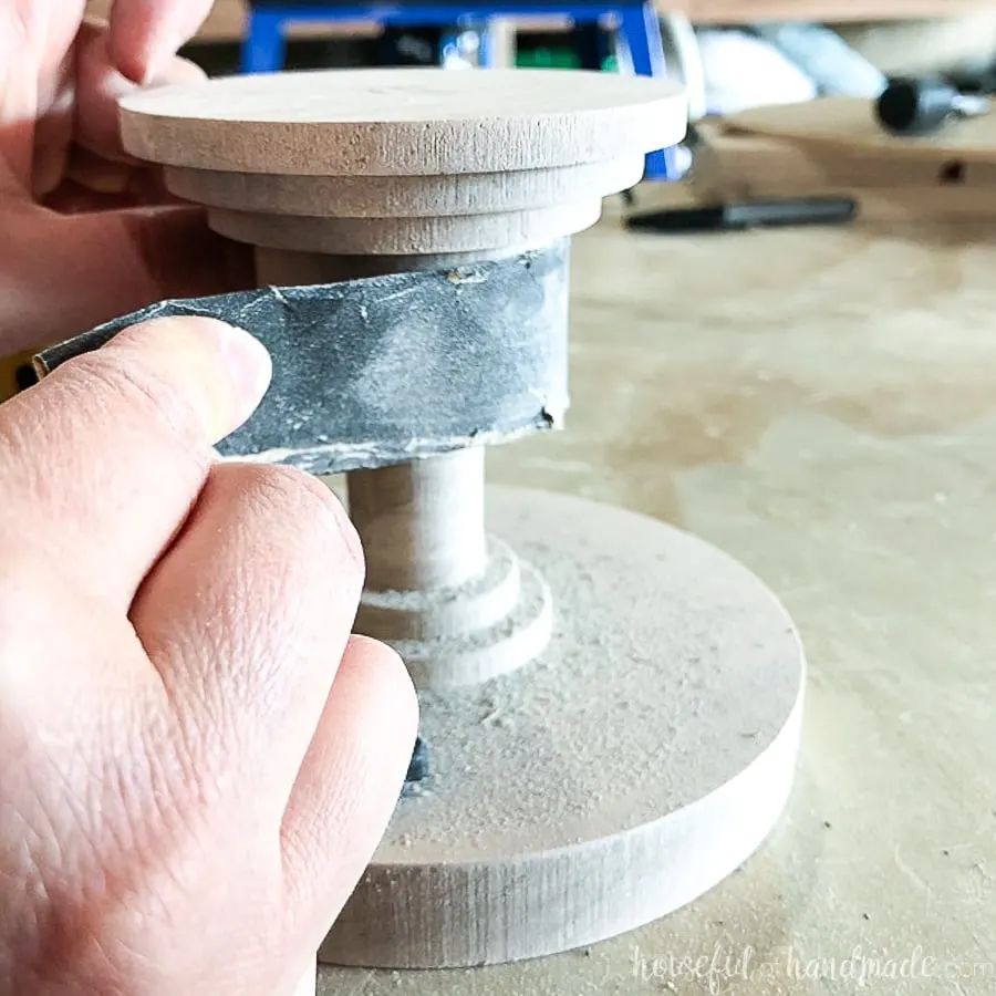 Hand sanding the base of the DIY wood cake stand.