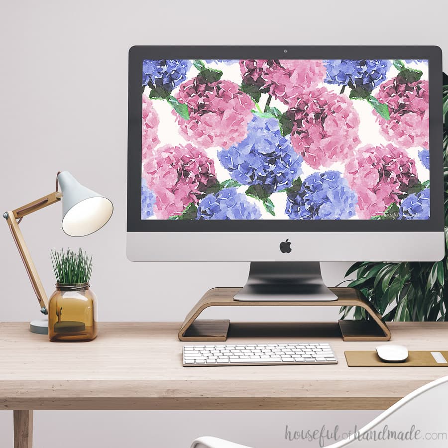 Computer on a desk with the free digital background for May on it.
