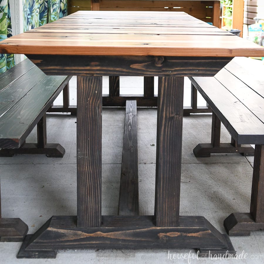 Side of the wood picnic table with dark base and redwood top.