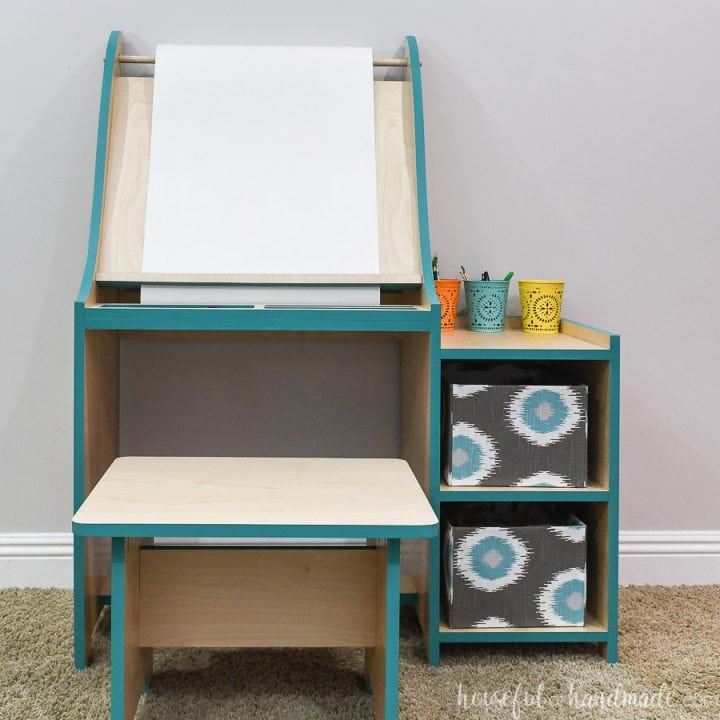 Front view of the art easel for kids with shelves for storage and bench to sit on.