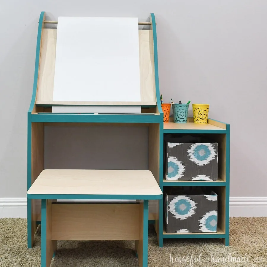 Front view of the art easel for kids with shelves for storage and bench to sit on.