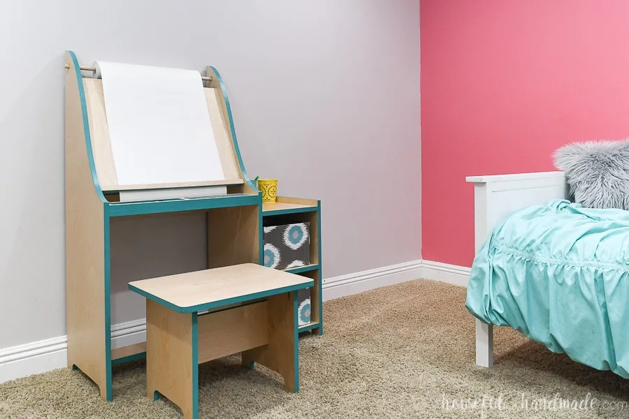 Girls bedroom with daybed on pink accent wall and kids art easel with turquoise accents on the other wall. 