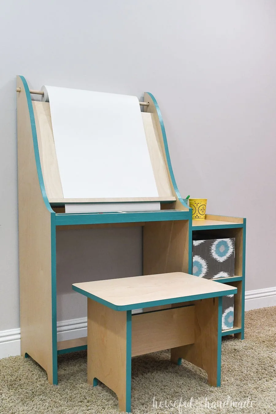 Kids art easel made from wood with shelves on the side and matching bench. 