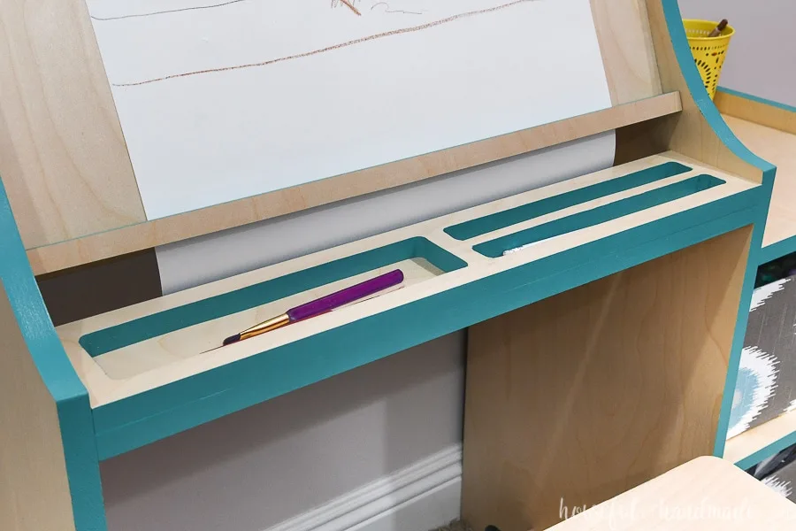 Pencil tray on the art easel for kids with teal painted edges. 