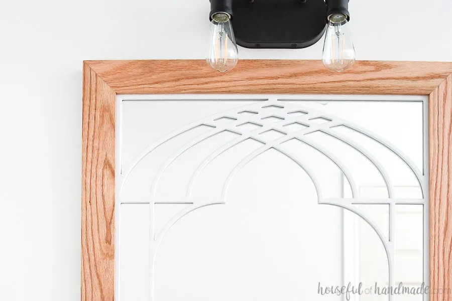 Close up of the top carved detail on the unique bathroom mirror with cathedral arch window frame design. 