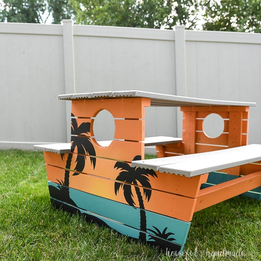 Kids picnic table with engineered decking top and seats and painted to look like a tropical sunset.