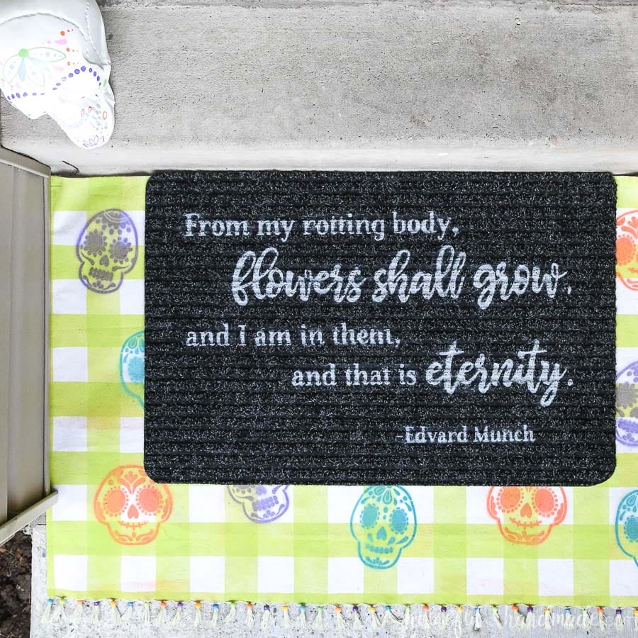 Closup of the DIY Halloween layered doormat with sugar skulls and a Day of the Dead quote. 