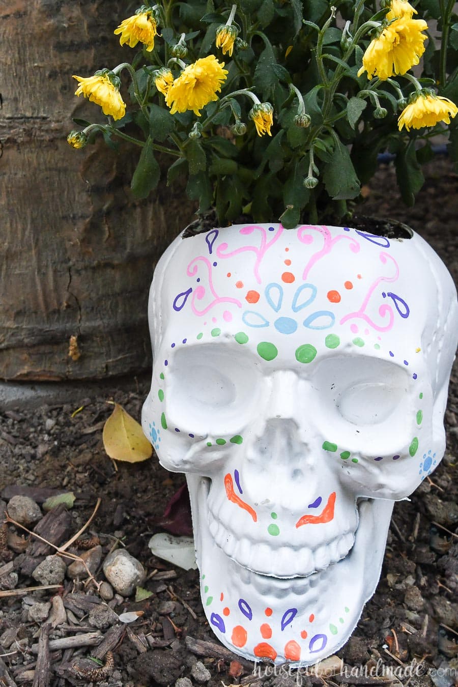 White DIY sugar skull pot with yellow mums planted in them. 