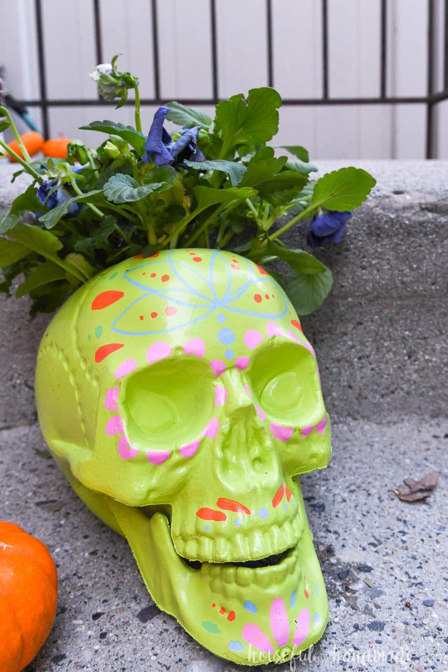 Lime green sugar skull planter with colorful decorations around the face. 