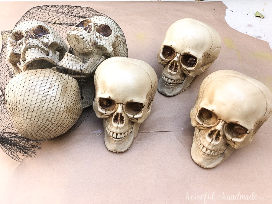 Three plastic skulls in a bag and three more outside of the bag on brown paper. 