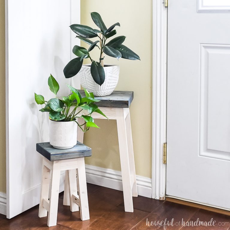 Nesting plant stands with navy stained tops holding plants in the corner.