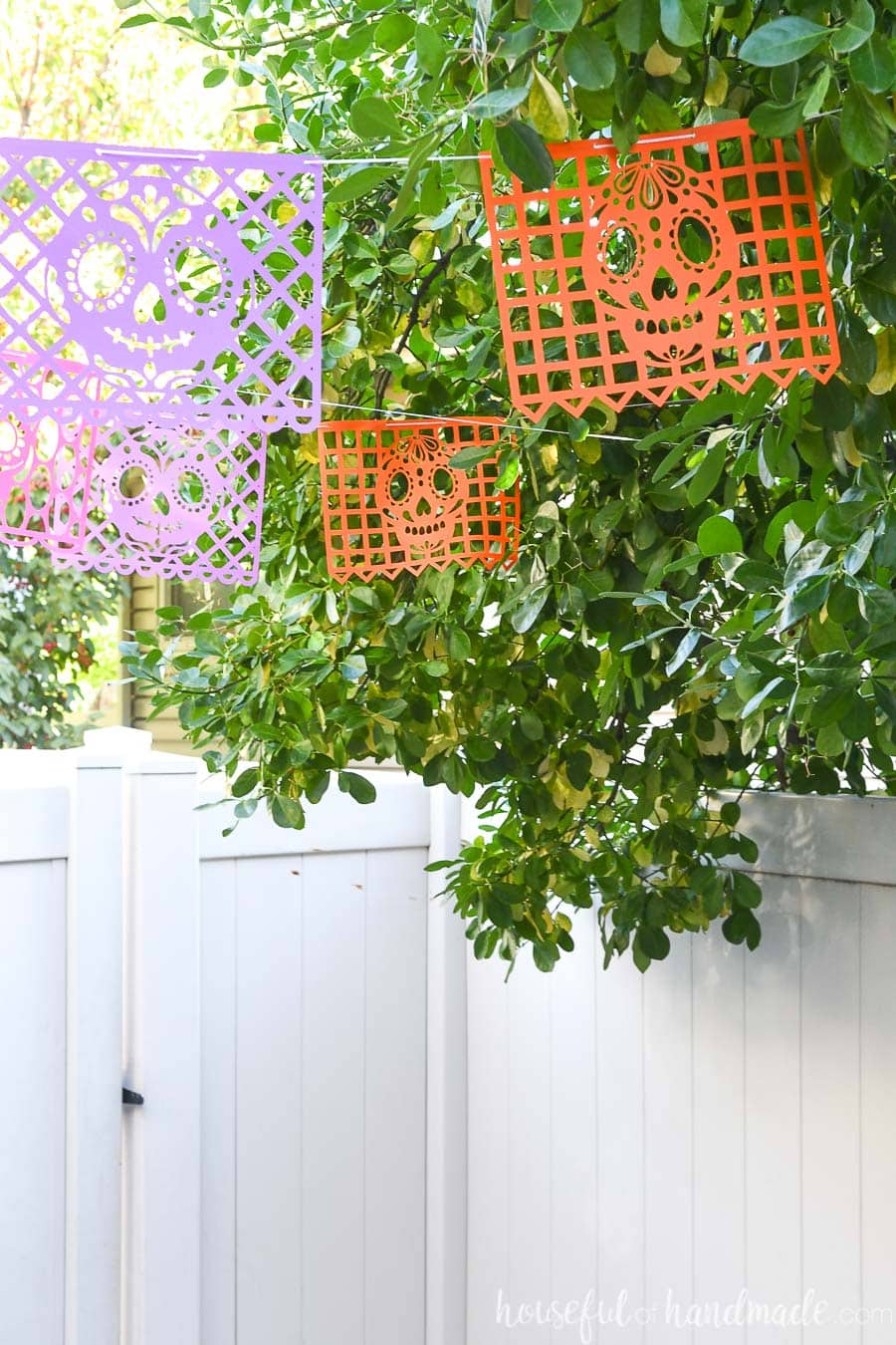 Orange and purple Day of the Dead banners hanging in a tree.