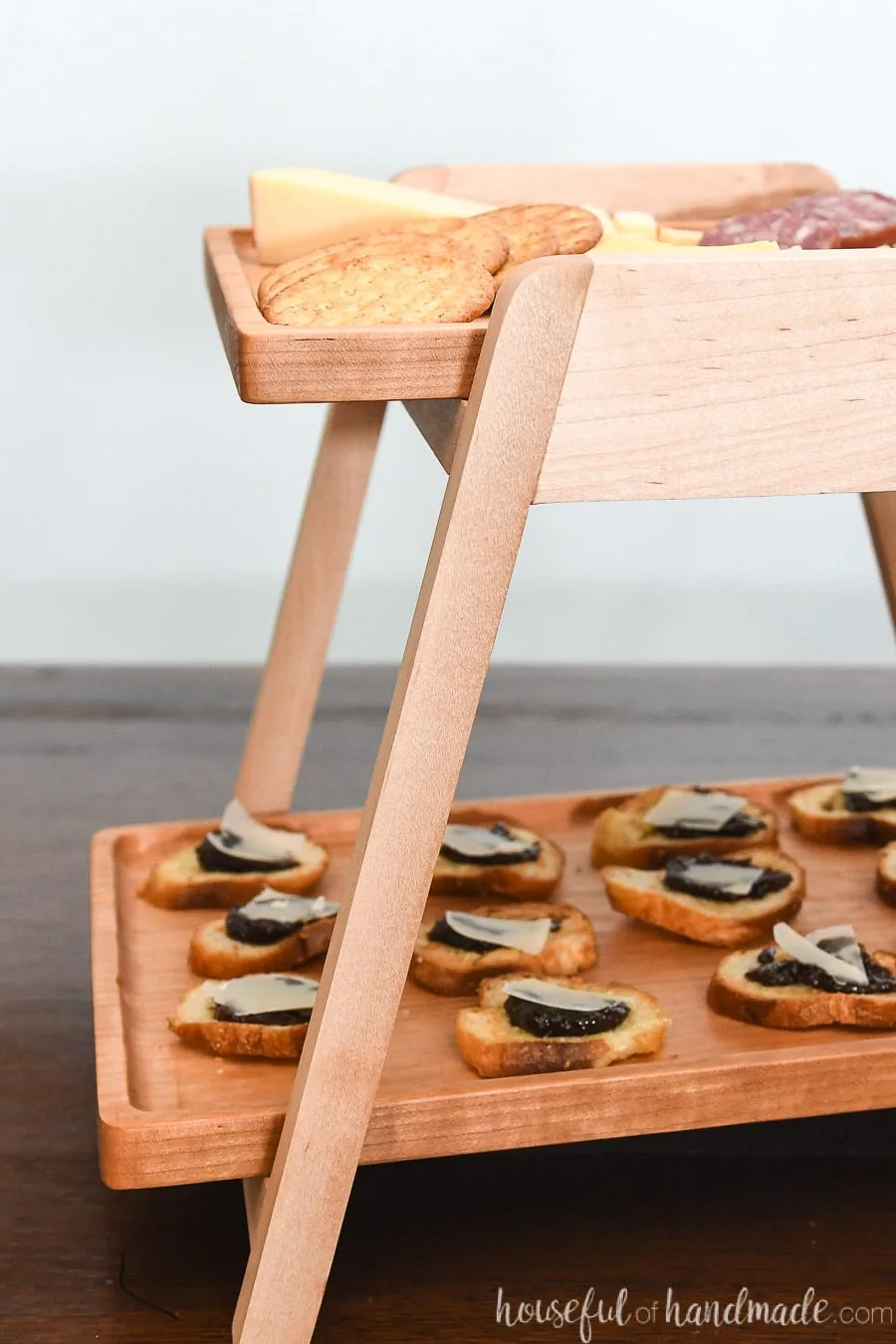 Close up view of the white maple stand holding the 2 wood serving trays. 