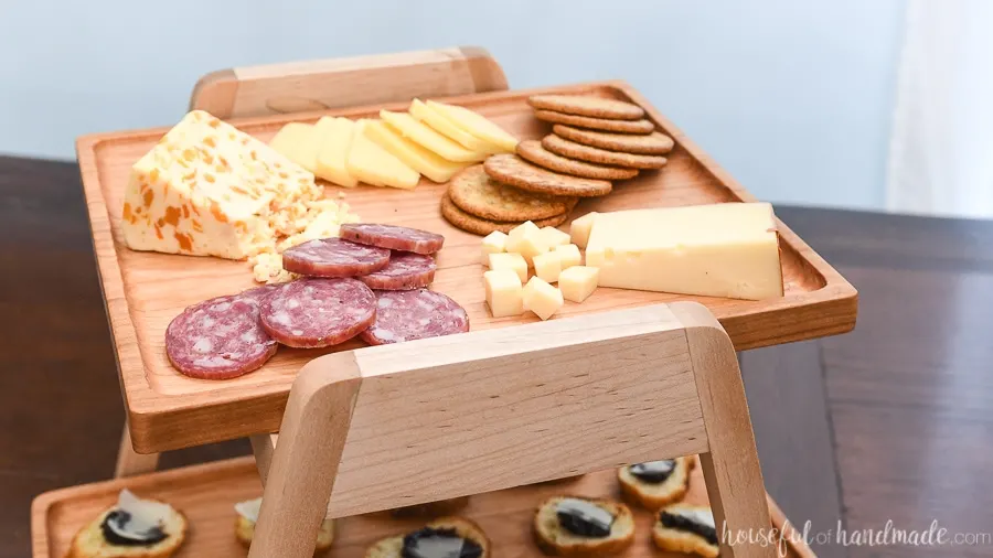 Close up of the top serving tray holding cheeses and crackers on the tiered serving tray. 
