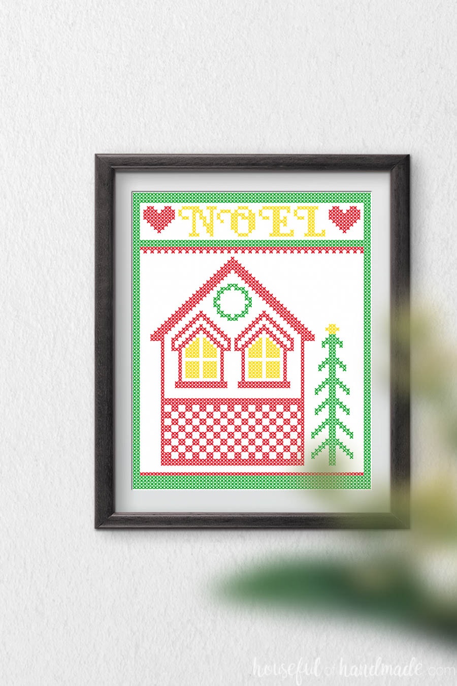 Cross-stitch house with a frame and Noel around it as printable Christmas art. 