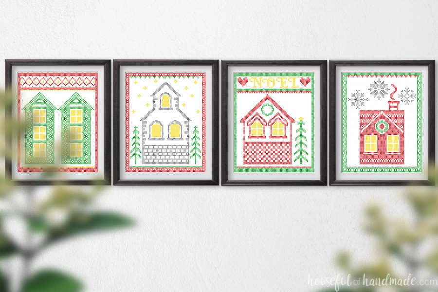 Four cross-stitched village printable art pieces in frames on a wall. 