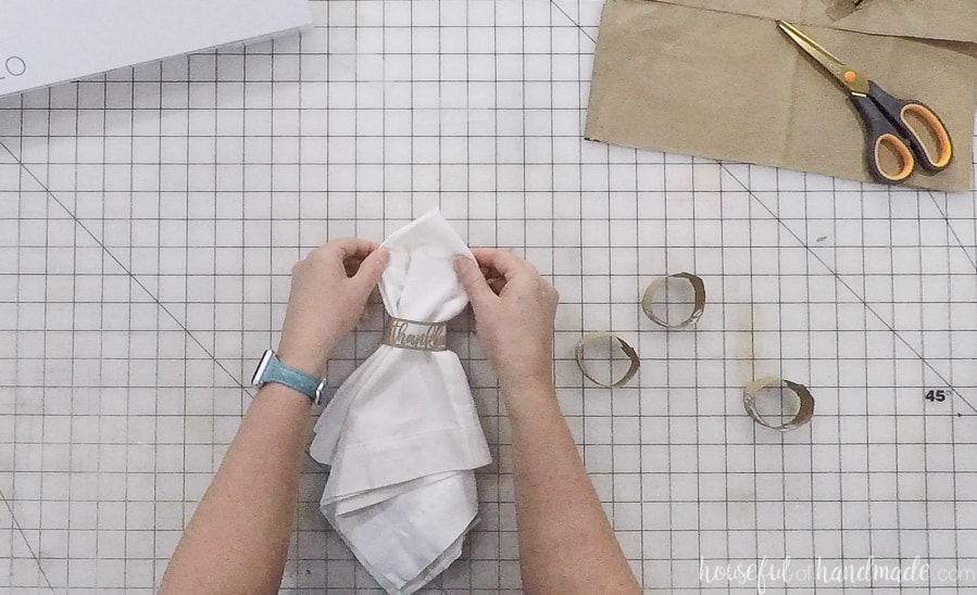 Sliding a white napkin into the DIY thanksgiving napkin ring.