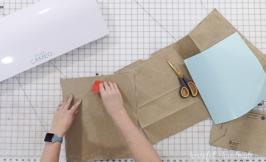 Putting the brown paper on a Silhouette cutting mat.