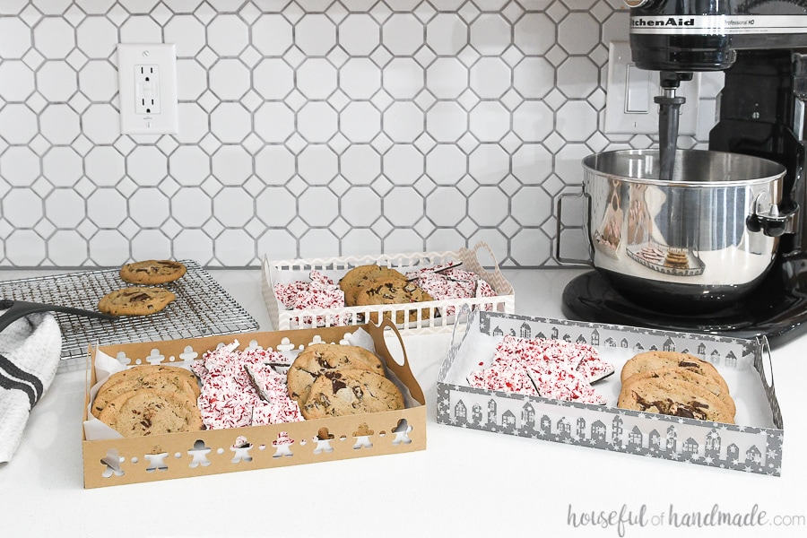 Three Christmas trays made from paper with cookies and treats inside them.