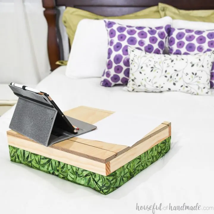 DIY lap desk with storage on a bed with an iPad and paper on it.