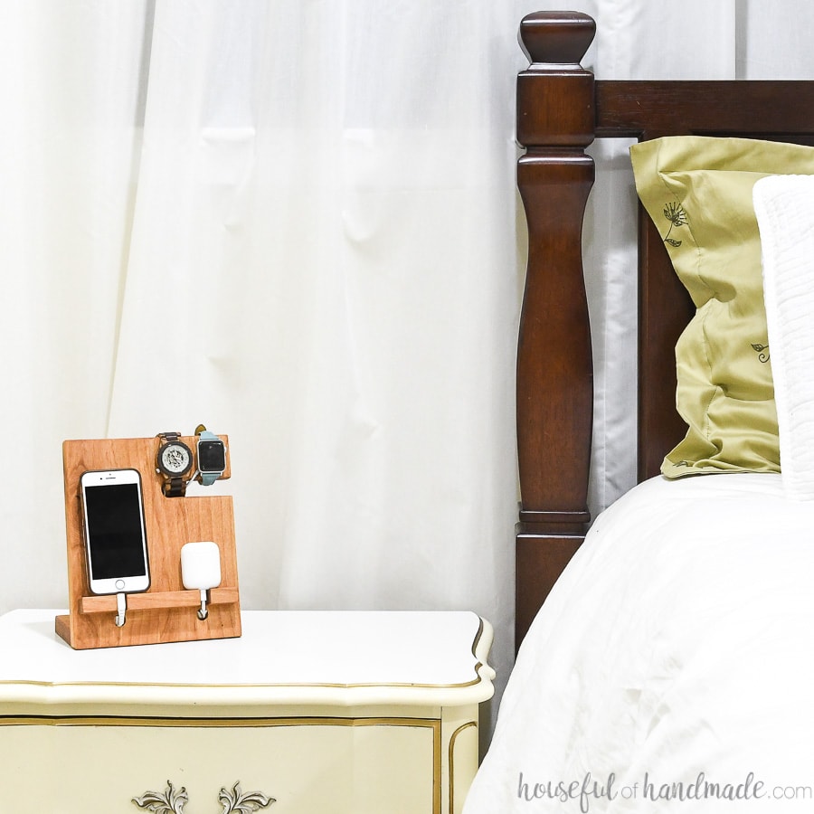 Wood valet holding phone, watch and bluetooth earbuds while charging next to the bed.