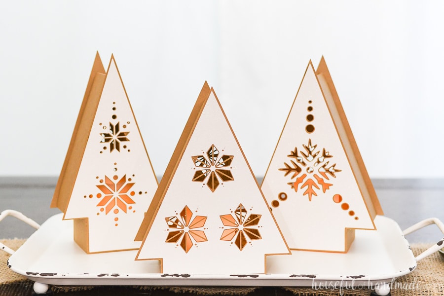 Three Nordic Christmas tree lanterns on a tray made out of paper.