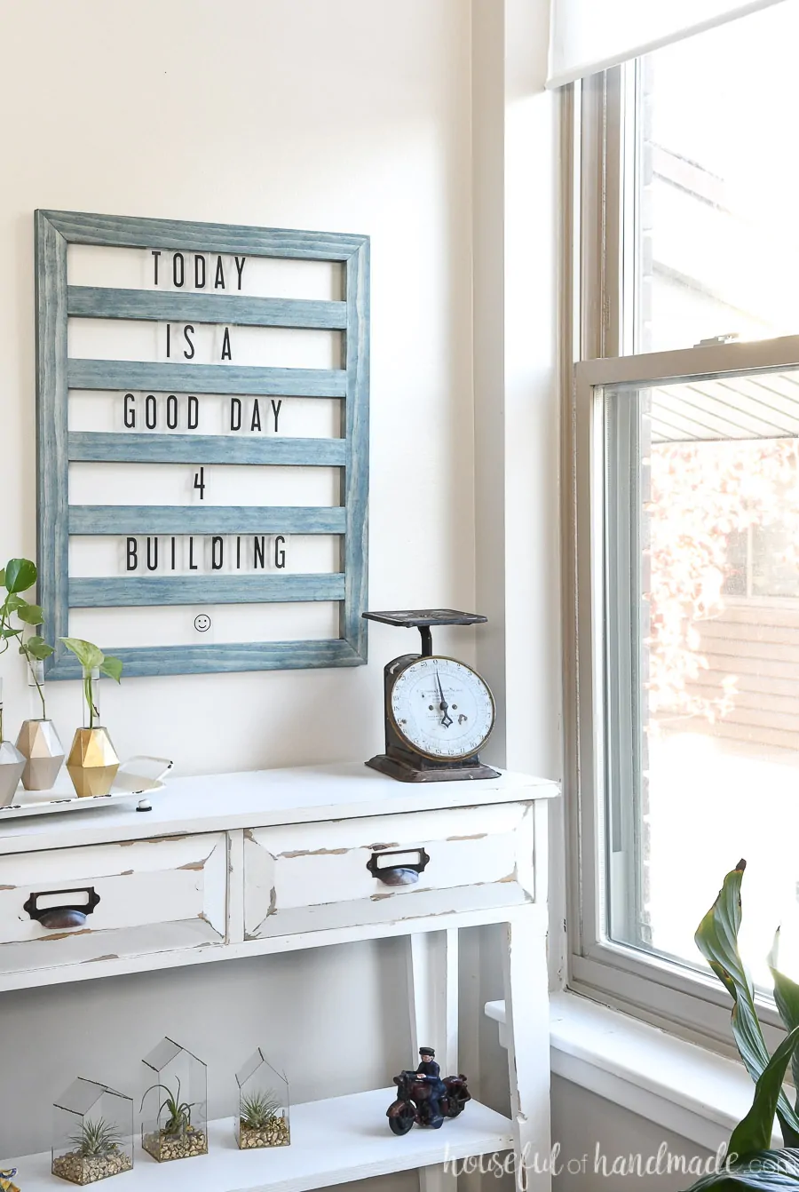 Corner of a room overlooking the window with a farmhouse console table decorated with a DIY letter board above it. 