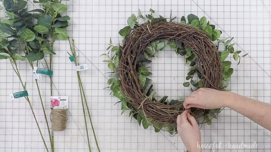 Tying twine to the top of the wreath to hang it easily.