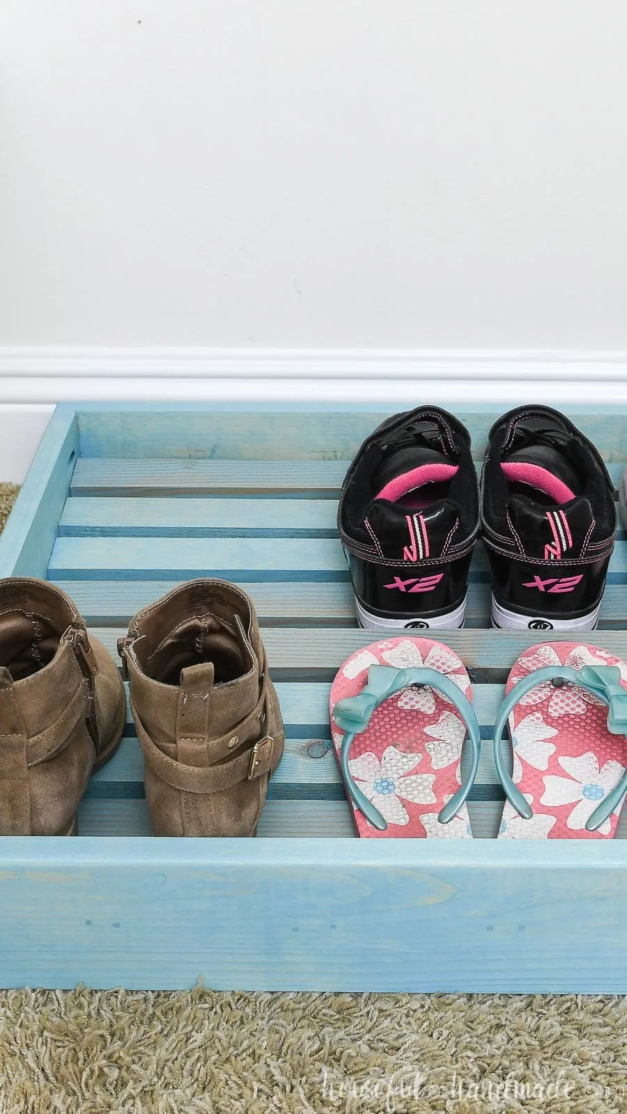 Close up view of the easy to build shoe organizer tray on the floor of the closet with shoes in it.