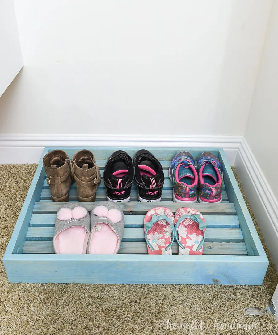 Turquoise stained wood shoe rack in the closet. 