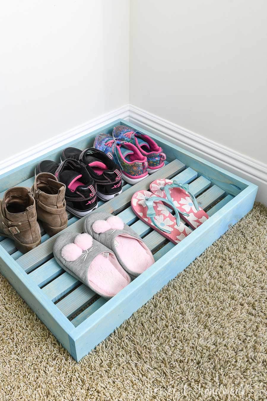 Five pair of kids shoes organized on the shoe storage tray in the closet.