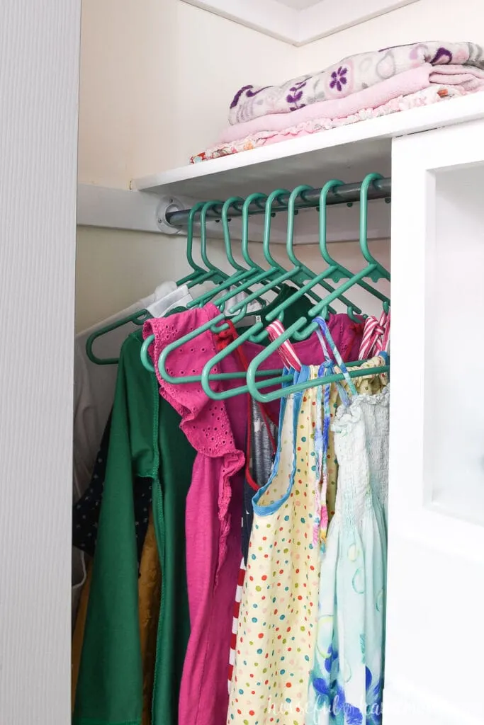 Closet rod with dresses hanging on teal hangers. 