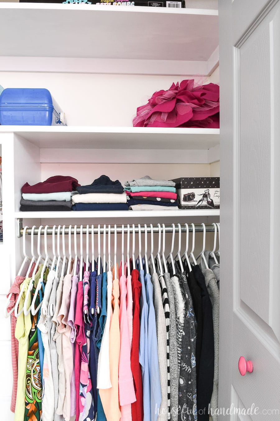 Pants stored on a shelf above the closet rod in the closet. 