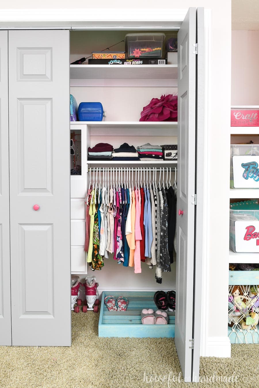 Girls organized closet with gray closet doors, one which is open showing the clothes hanging inside.