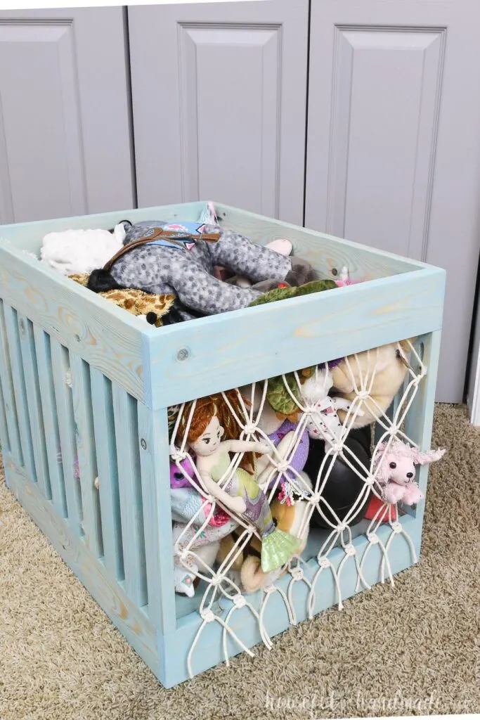 Turquoise stained wood bin turned into stuffed animal storage with a simple macrame net on the front & back.