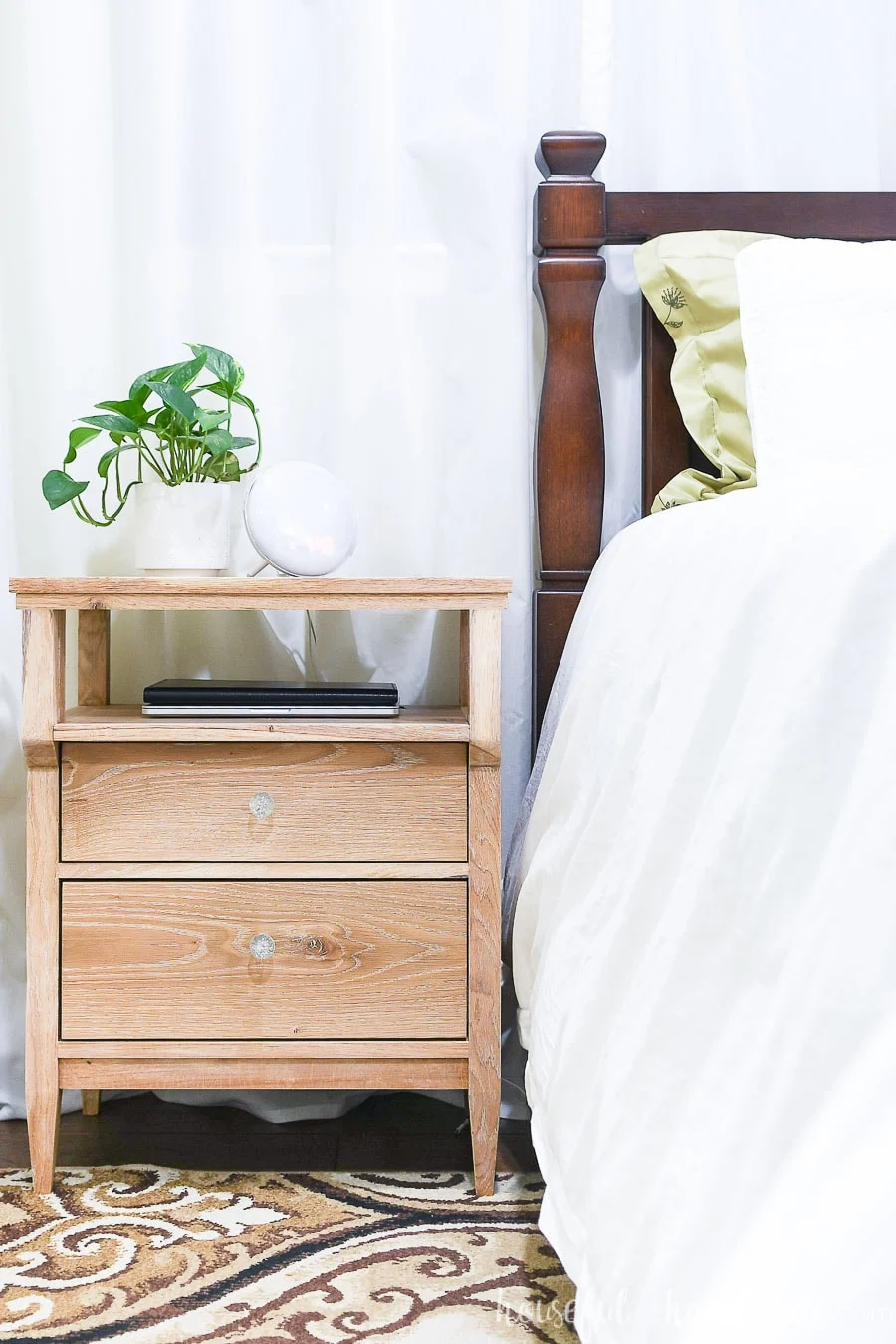 Gorgeous DIY solid wood nightstand with tapered legs next to bed with white duvet.
