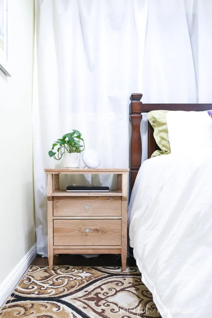 DIY tall nightstand with a plant on top next to the bed.