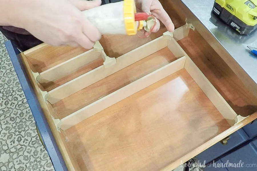 Adding glue to the inside of the wood clip to make them permanently attached to the drawer dividers. 