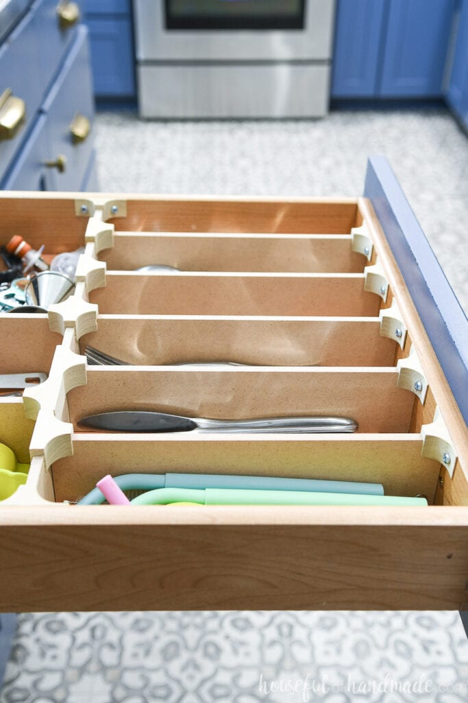 Side view of the perfectly organized silverware drawer with all the clips holding the drawer dividers together. 