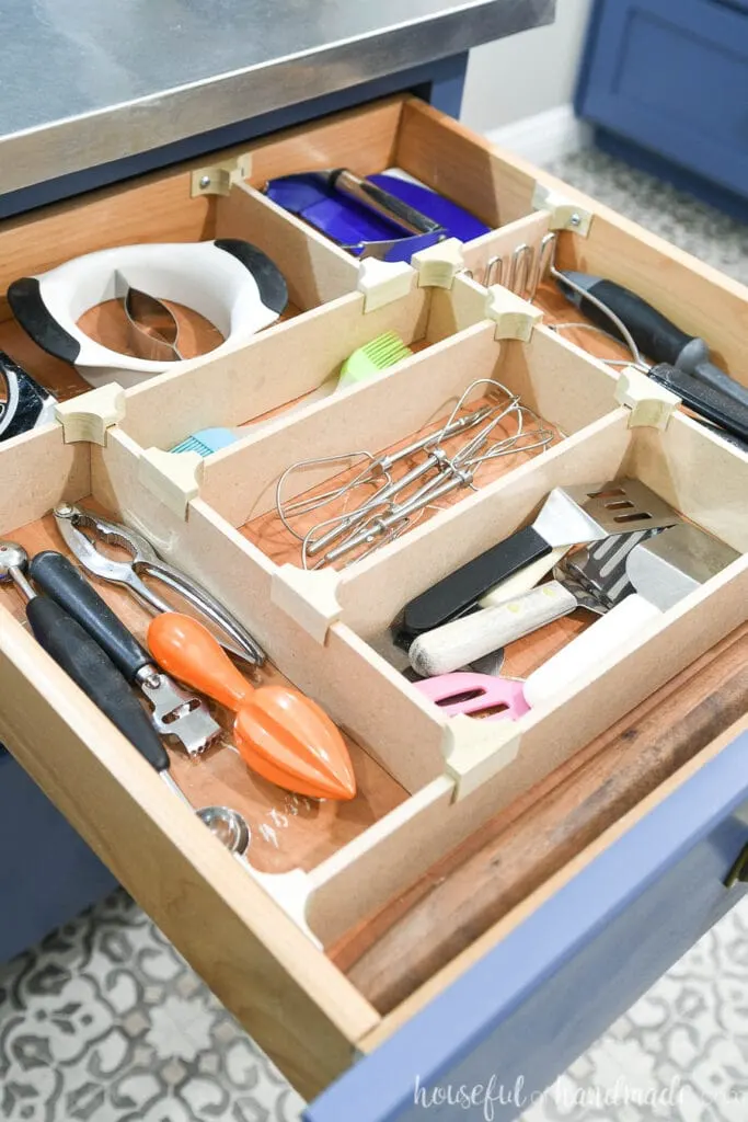 Kitchen drawer organized with all the utensils in separate compartments, separated with wood drawer dividers held together with wood clips. 