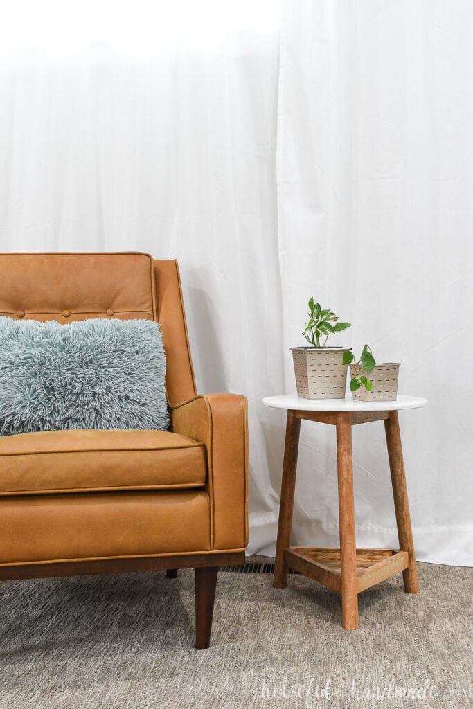Living room with chair and end table holding houseplants in paper flower pots.