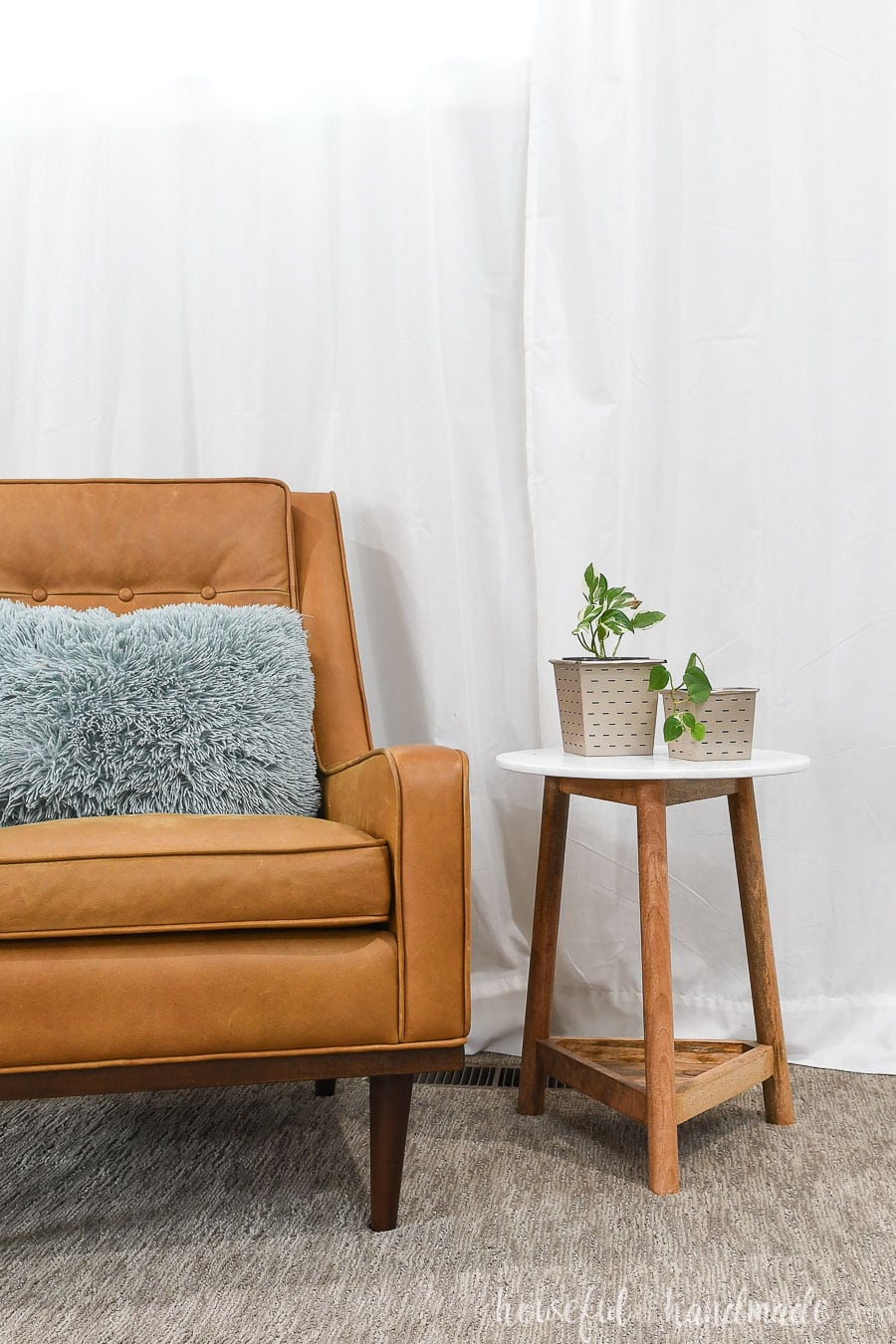 Living room with chair and end table holding houseplants in paper flower pots. 