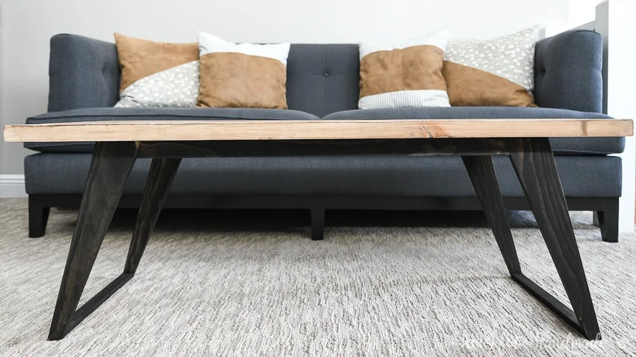 Straight on view of the modern coffee table with angled legs stained black and warm wood top. 